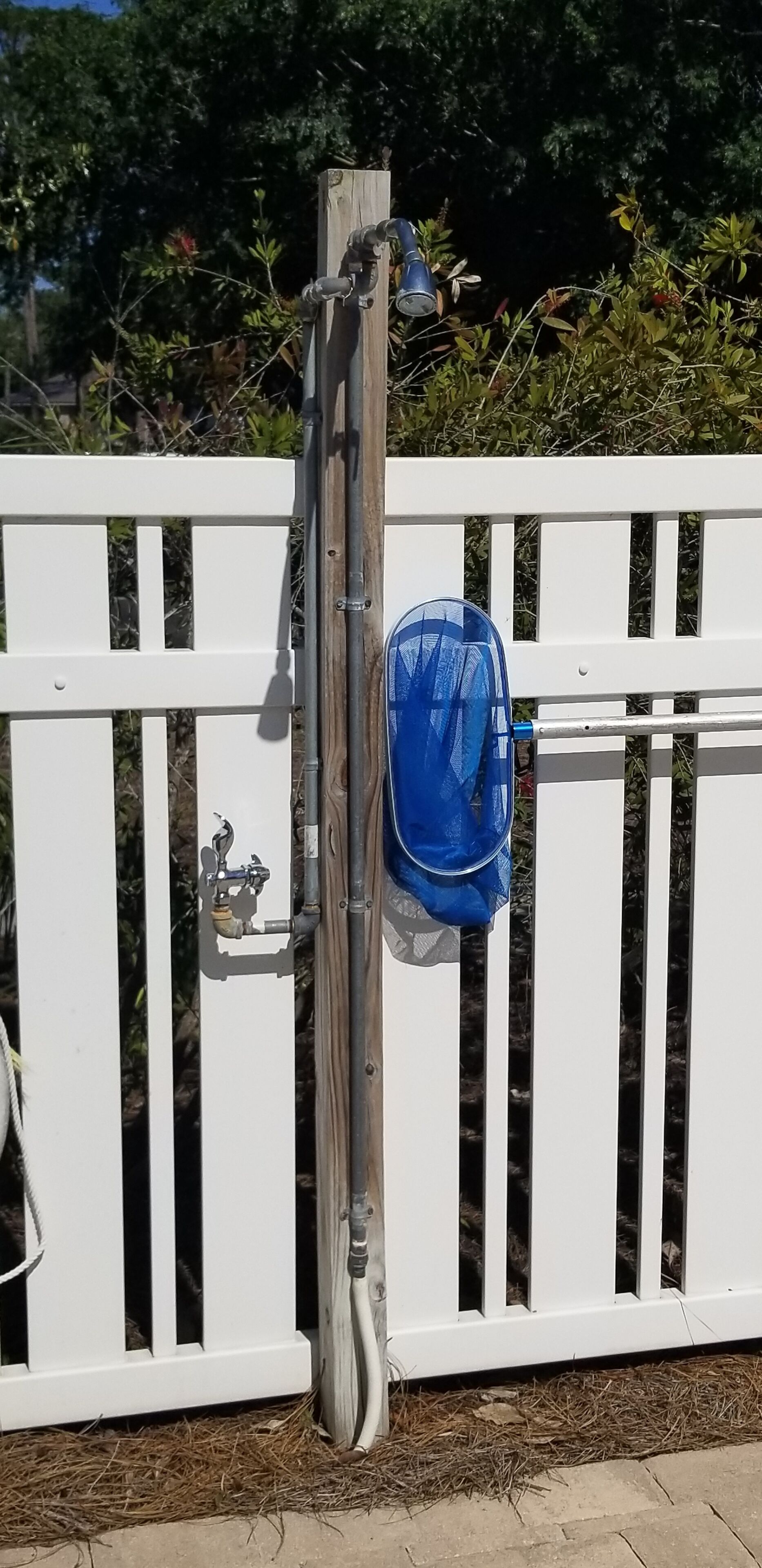 Uma cerca de madeira branca com um saco plástico azul pendurado num suporte de metal.