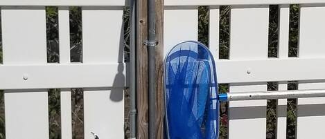 Uma cerca de madeira branca com um saco plástico azul pendurado num suporte de metal.