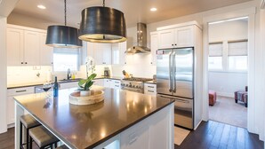 A modern kitchen with a central island, stainless steel appliances, and pendant lighting. - Bring bikes + SUP and have summer Bend fun! 24-hr staff ~ tons of room ~ resort  (Bend)