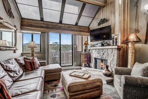 Relax in this mountain-view living room with a stone fireplace, leather sofas, and a flat-screen TV.