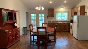 Una cocina amplia con armarios de madera, una mesa de comedor con sillas y un refrigerador.