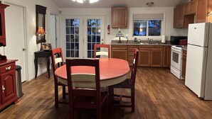 Una cocina con gabinetes de madera, un refrigerador blanco, una estufa, un lavadero y una mesa de comedor con sillas.