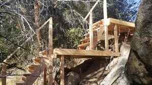 A wooden staircase leading up a rocky terrain, surrounded by trees and vegetation.