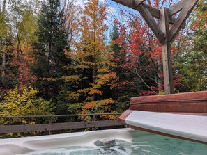 A hot tub with a wooden deck and a view of autumn trees. - Cozy, comfy, rustic ski chalet at the foot of Ski Brule ski mountain (Iron River)