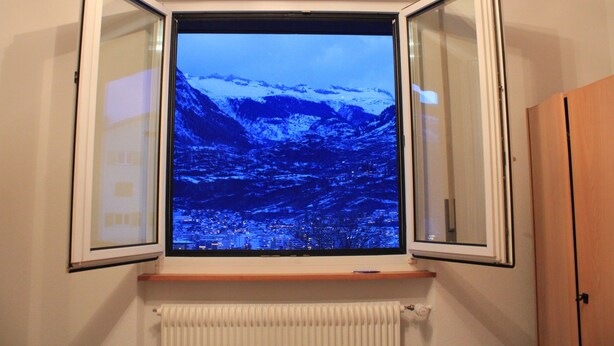 A room with a window overlooking a snowy mountain landscape.