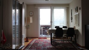 A dining area with a table and chairs, a potted plant, and a chessboard.