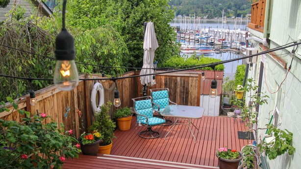 A wooden deck with outdoor furniture, potted plants, and a view of a marina. - Poulsbo Marina and Olympic Hideaway View (Poulsbo)