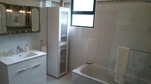 Een bad/douchecombinatie, een haardroger, een bidet, handdoeken