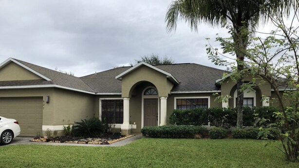 A residential house with a garage, a driveway, and a well-maintained lawn. - Beautiful Home near Walt Disney World   (Davenport)