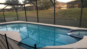 A swimming pool with a curved edge and a small hot tub area. - Beautiful Home near Walt Disney World   (Davenport)