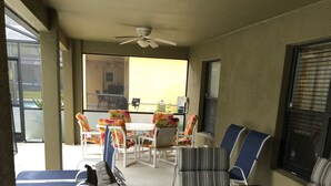 A covered outdoor seating area with a table and chairs, a ceiling fan, and a view of the outside. - Beautiful Home near Walt Disney World   (Davenport)