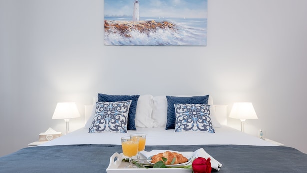 A neatly made bed with a blue blanket, two pillows, a tray with croissants, orange juice, and a rose. - "City and Sea" apt in center, 5 min walk to the Diocletian’s palace and beach  (Split)