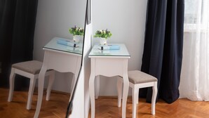 A room with a white chair and table, a potted plant on the table, and a mirror reflecting the room. - "City and Sea" apt in center, 5 min walk to the Diocletian’s palace and beach  (Split)