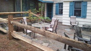 Un patio con un columpio de madera, una mesa redonda y dos sillas.
