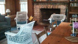 Una habitación acogedora con sillas de mimbre, una mesa de madera y una chimenea de piedra.