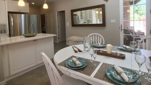 A modern kitchen with white cabinetry, a stainless steel refrigerator, and a dining area with a white table set for four. - Feel at Home , all sanitized, 6 walkable blocks from Santa Fe Plaza. (Santa Fe)