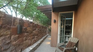 A stone wall, a chair, and a table outside a building. - Feel at Home , all sanitized, 6 walkable blocks from Santa Fe Plaza. (Santa Fe)