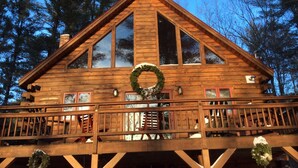Una cabaña de madera con balcón, ventanas amplias y una decoración con corona.