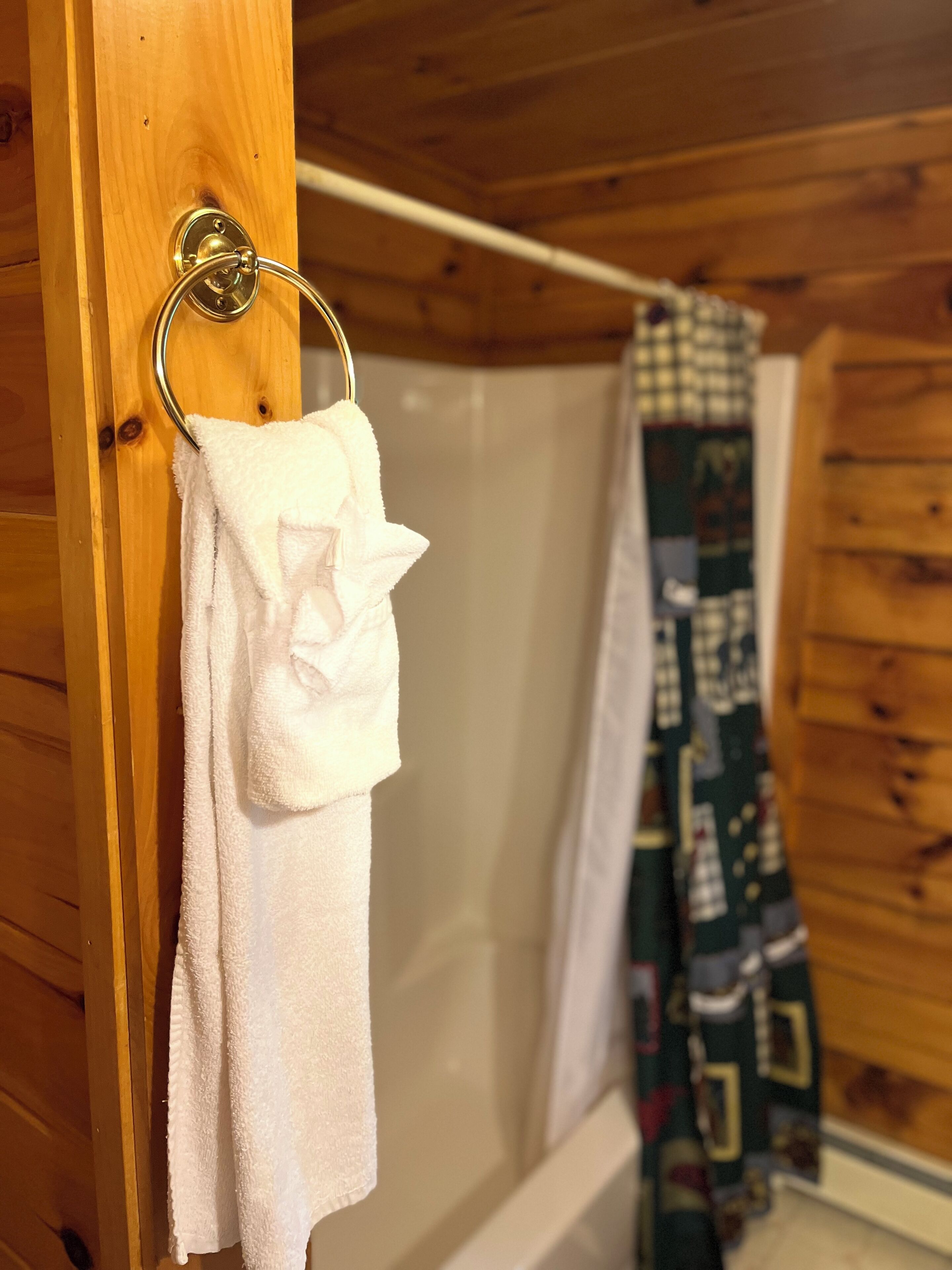 A wooden cabin bathroom with a white towel hanging on a metal towel ring.