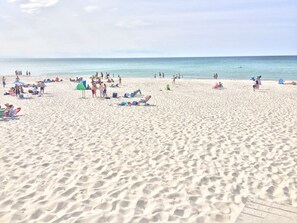 Una playa arenosa con gente y sombrillas.