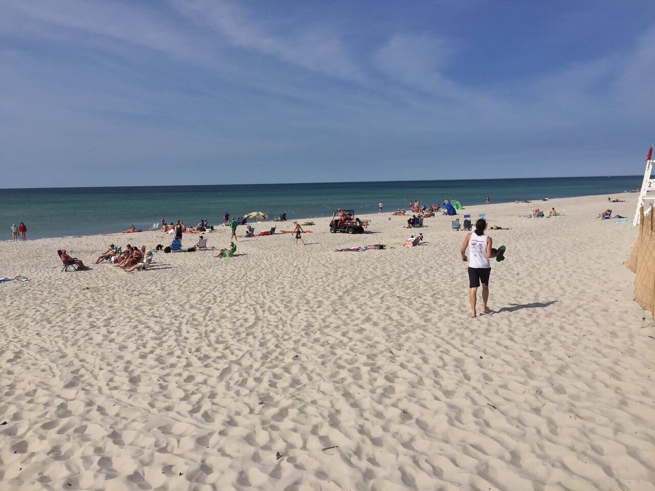 A sandy beach with people sunbathing and walking.