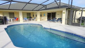 A swimming pool with a blue tiled edge, surrounded by lounge chairs and a covered patio area. - LUXURY FOR YOU + Last-Minute-Rates: 2 Masters, Gas Grill, TV65" 4K & Game Room (Davenport)