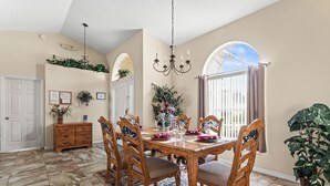 A dining room with a wooden table, six chairs, a chandelier, and potted plants. - LUXURY FOR YOU + Last-Minute-Rates: 2 Masters, Gas Grill, TV65" 4K & Game Room (Davenport)