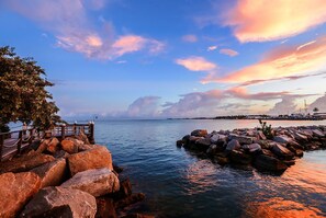 A coastal scene with a wooden pier, rocky breakwaters, and a clear view of the sea. - Galleon Resort Efficiency in the old town (Key West)