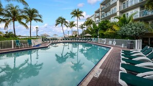 A swimming pool with lounge chairs and palm trees, surrounded by a multi-story building with balconies. - Galleon Resort Efficiency in the old town (Key West)