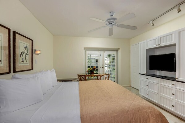 A hotel room with a bed, a ceiling fan, a TV, and a dining area with a table and chairs. - Galleon Resort Efficiency in the old town (Key West)