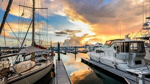 A marina with various boats docked, a wooden walkway leading to the water, and a sunset in the background. - Galleon Resort Efficiency in the old town (Key West)