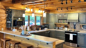 A spacious kitchen with wooden beams, a central island with stools, and modern appliances.