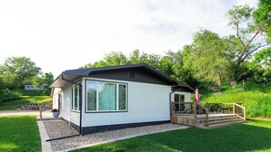 A modern single-story house with a covered porch, a small deck, and a well-maintained lawn. - Charming Lake House within Walking Distance from Lake (Yankton)
