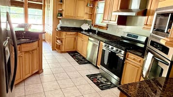 A kitchen with wooden cabinets, a stainless steel refrigerator, a stove, and a microwave.