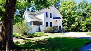 A two-story house with a front porch, a driveway, and a well-maintained lawn. - Escape to the Beech House: A Wooded Family- Friendly Retreat Close to the Beach! (Kitty Hawk)
