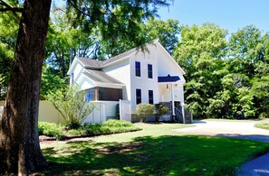 A two-story house with a front porch, a driveway, and a well-maintained lawn. - Escape to the Beech House: A wooded family friendly retreat near the beach! (Kitty Hawk)