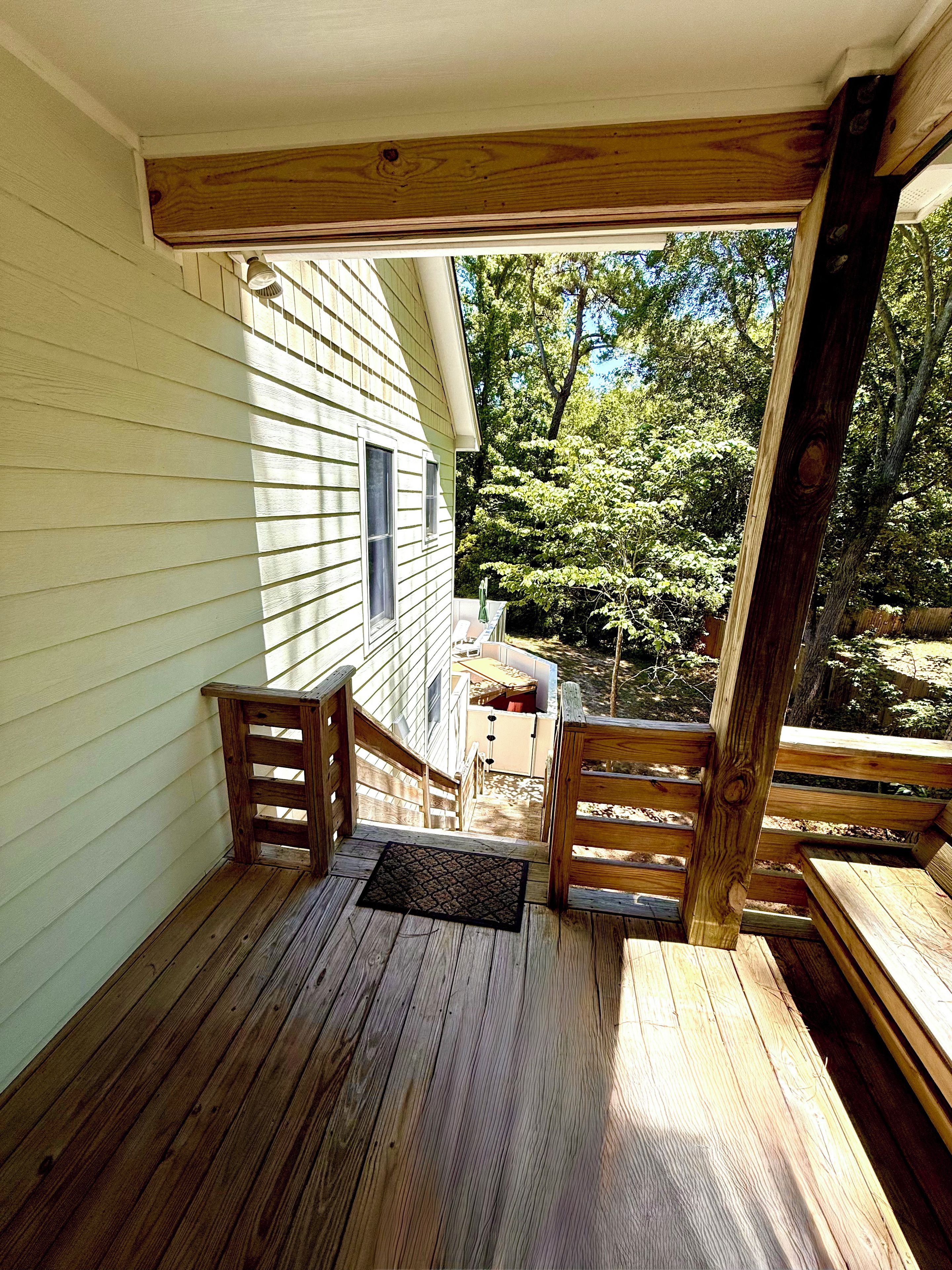 A wooden deck with a view of a house and trees.