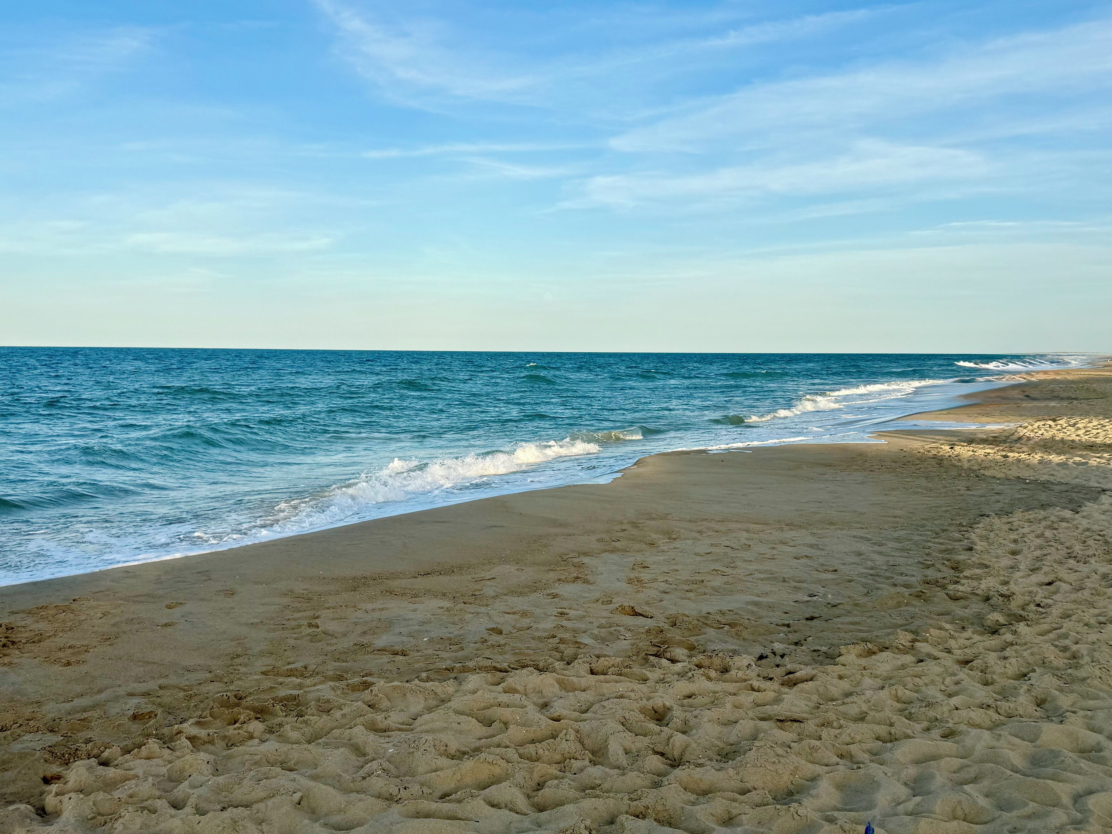A beach with a sandy shore and waves approaching the beach.