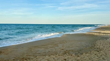 A beach with a sandy shore and waves approaching the beach.