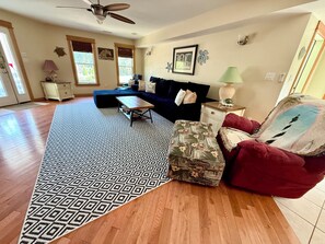 A spacious living room with a dark blue sofa, a patterned rug, and a red armchair.