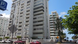 Un edifici residencial de diverses plantes amb balcons, un portal tancat amb reixa i un senyal de pàrquing.
