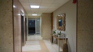 Passadís amb terra de rajola, taulell de recepció amb mirall i plantes, i porta amb el número 5.
