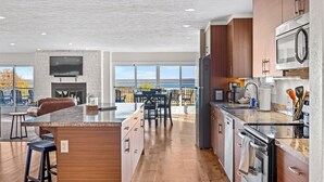 A modern kitchen with a large island, built-in appliances, and a view of the outdoors. - Panoramic lake view retreat with firepit! Centrally located on Wine Trail! (Penn Yan)