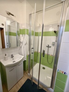 Une salle de bain avec une douche à parois de verre, un lavabo et un miroir.