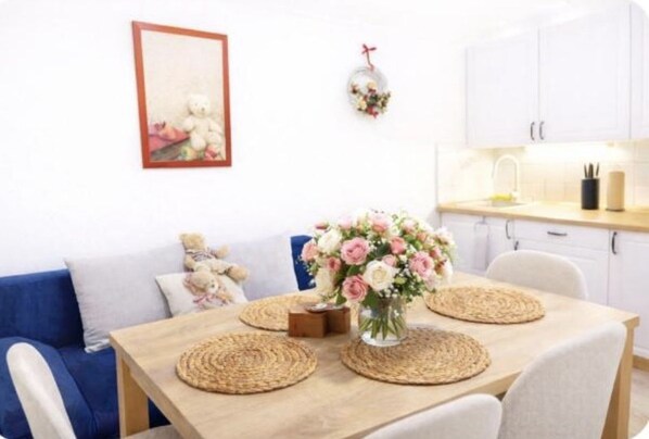 A dining area with a wooden table, woven placemats, and a vase of flowers.