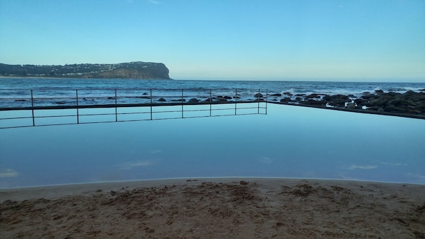 En infinitypool med utsikt över havet och en klippig kustlinje.