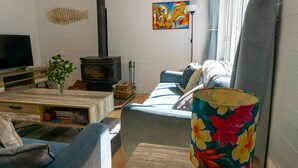 Ett mysigt vardagsrum med en soffa, ett soffbord, en tv, en öppen spis och en färgglad lampa.
