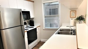A compact kitchen with a refrigerator, stove, microwave, and sink. - Best of Pawleys Plantation!   Inviting Retreat for Golfers and Beach Lovers (Pawleys Island)