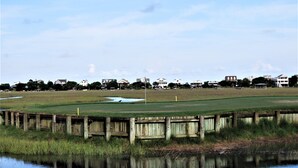 A golf course with a wooden fence and a body of water in the foreground. - Best of Pawleys Plantation!   Inviting Retreat for Golfers and Beach Lovers (Pawleys Island)