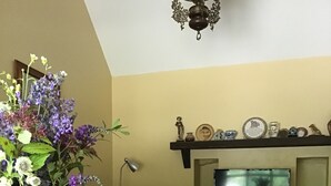 A living room with a checkered table, a sofa, a TV, and a decorative shelf with various items. -  Charming old-world country cottage, near Adare  (Kildimo)